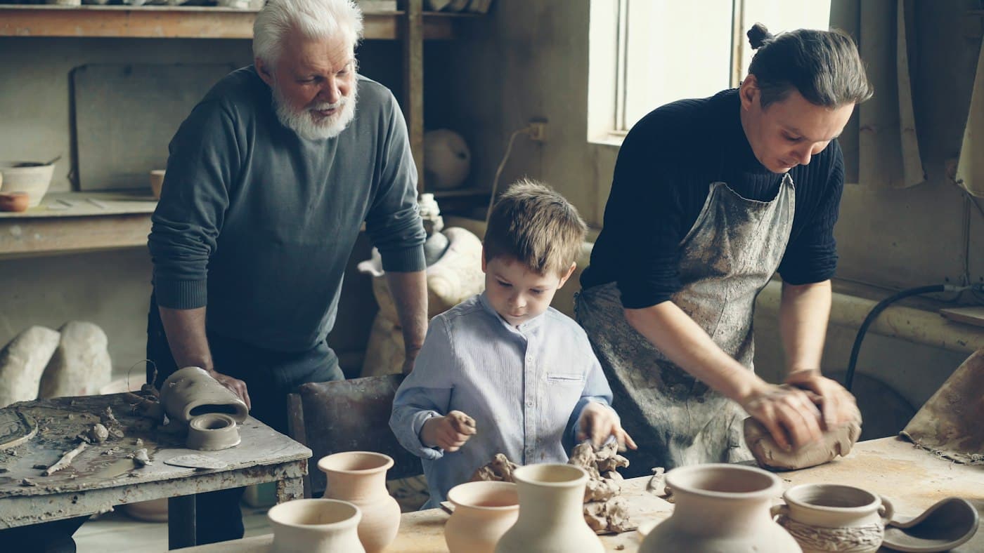 Abuelo, padre e hijo trabajando juntos en un taller de cerámica